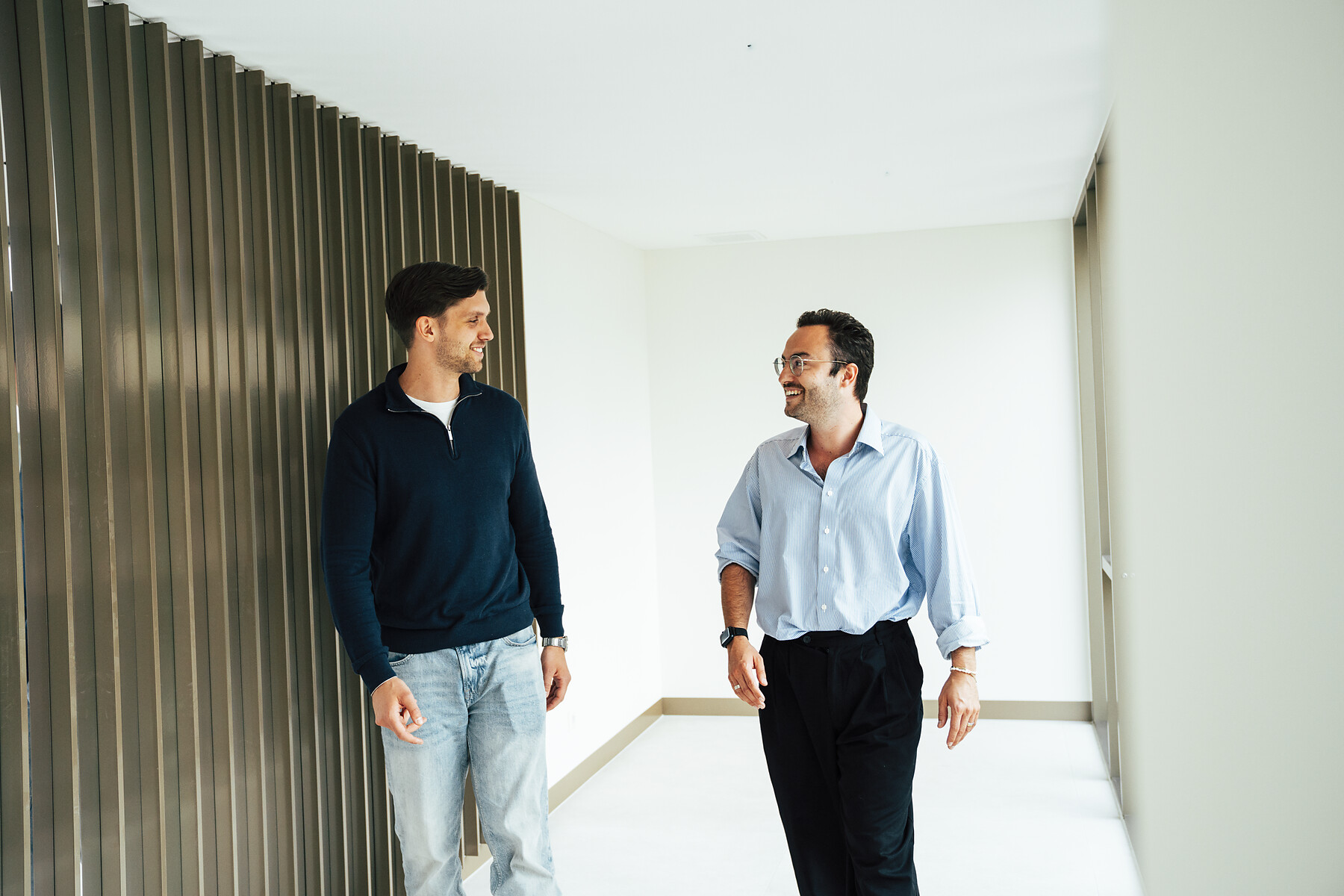 Twee Risers-collegas in gesprek in kantoorruimte met houten wand