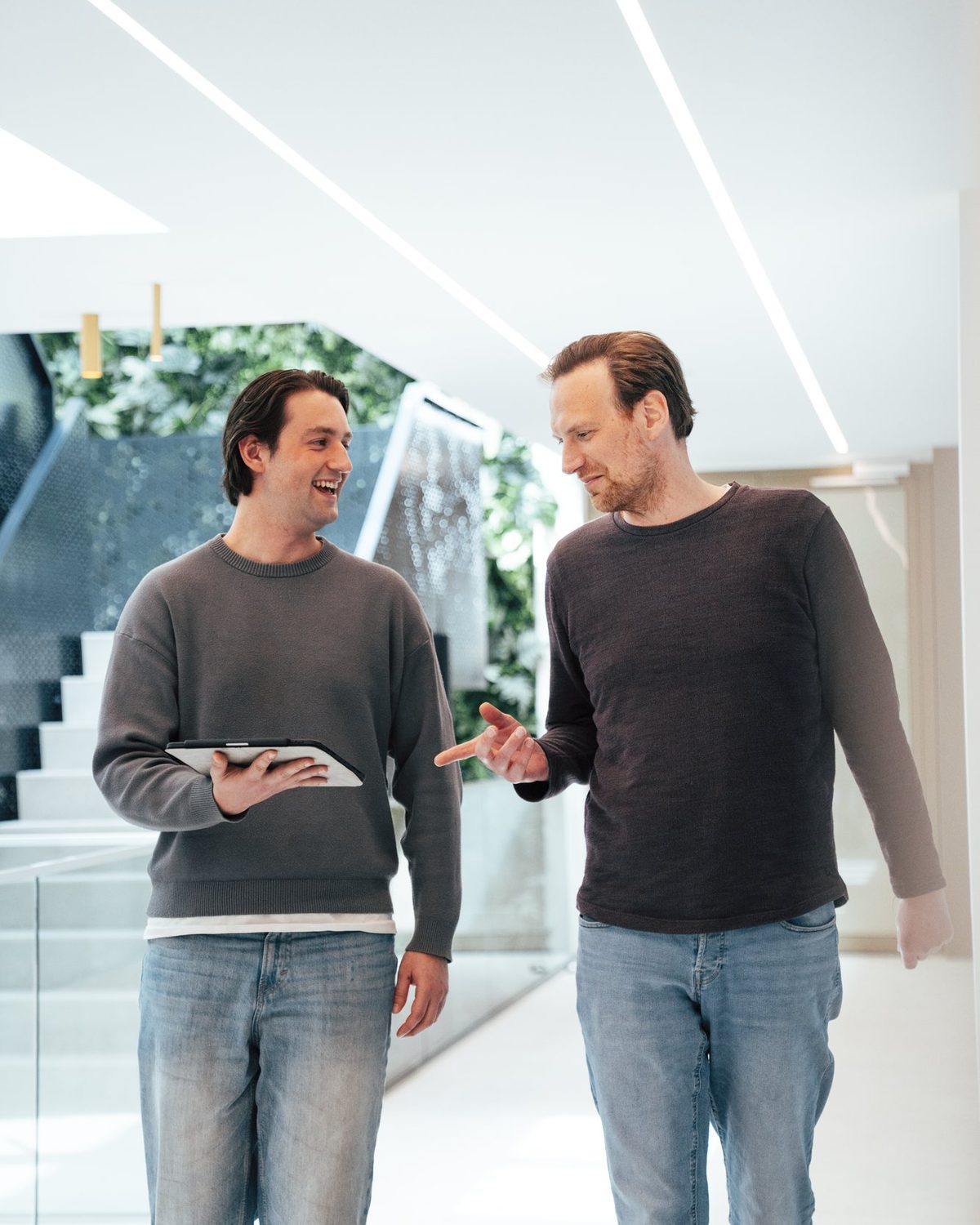 Twee Risers-collega's in gesprek terwijl ze door het kantoor lopen, een met een tablet